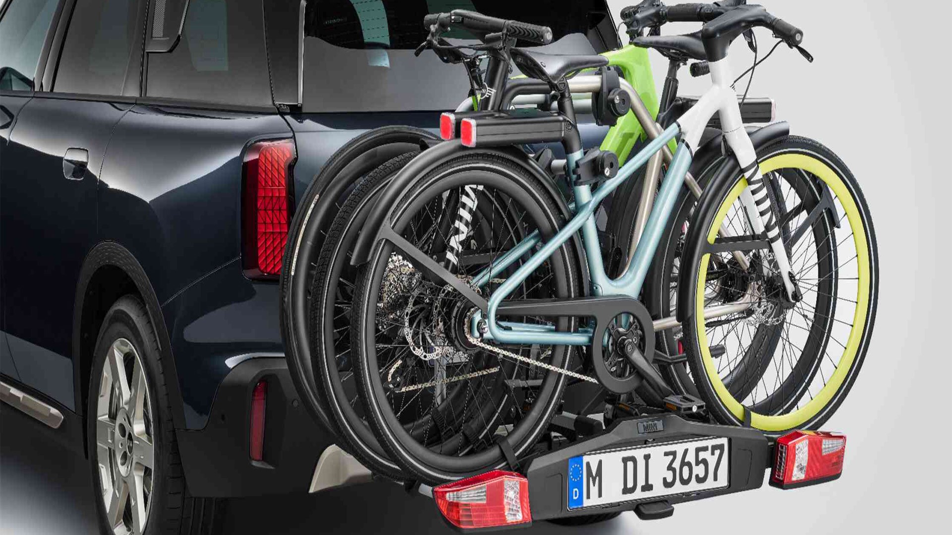 MINI Aceman in Nanuq White equipped with MINI rear bike rack Pro 3.0, carrying two mountain bikes and a child’s bike.